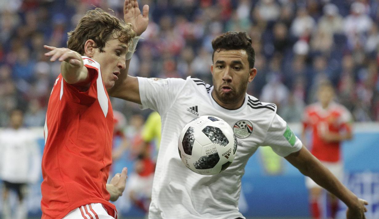 Gelandang Mesir, Trezeguet, berebut bola dengan bek Rusia, Mario Fernandes, pada laga Grup A Piala Dunia di Stadion Krestovsky, St Petersburg, Selasa (19/6/2018). Rusia menang 3-1 atas Mesir. (AP/Gregorio Borgia)