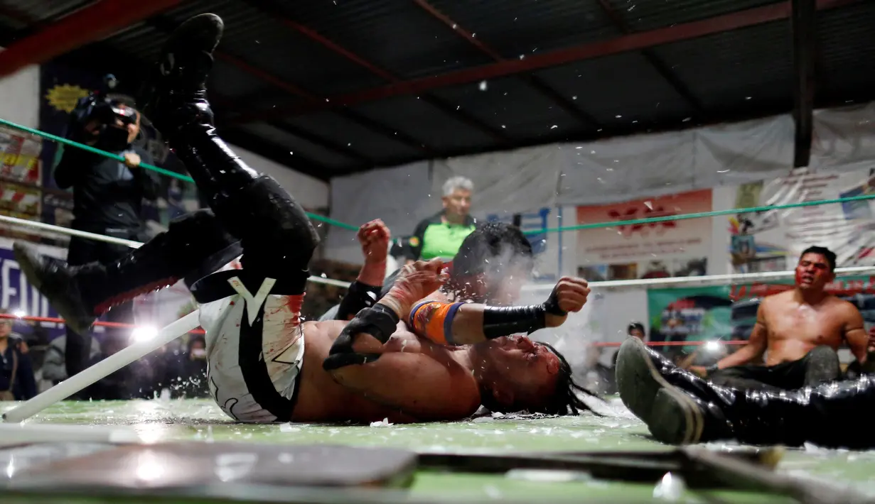 Pegulat yang dikenal sebagai Gio Malkriado menyerang lawannya, Ciclope dengan menggunakan lampu tabung panjang saat pertandingan gulat di Arena Neza di pinggiran Mexico City, Meksiko (28/10). (Reuters/ Carlos Jasso)