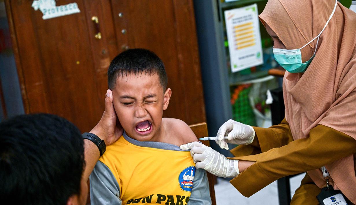 Seorang murid bereaksi saat menerima vaksin difteri di sebuah sekolah dasar di Surabaya pada Selasa 4 November 2025. Melalui kegiatan ini, pemerintah berupaya memastikan anak-anak terlindungi dari penyakit menular yang dapat dicegah melalui imunisasi, sekaligus menjaga kekebalan komunal di lingkungan sekolah. (Juni KRISWANTO/AFP)