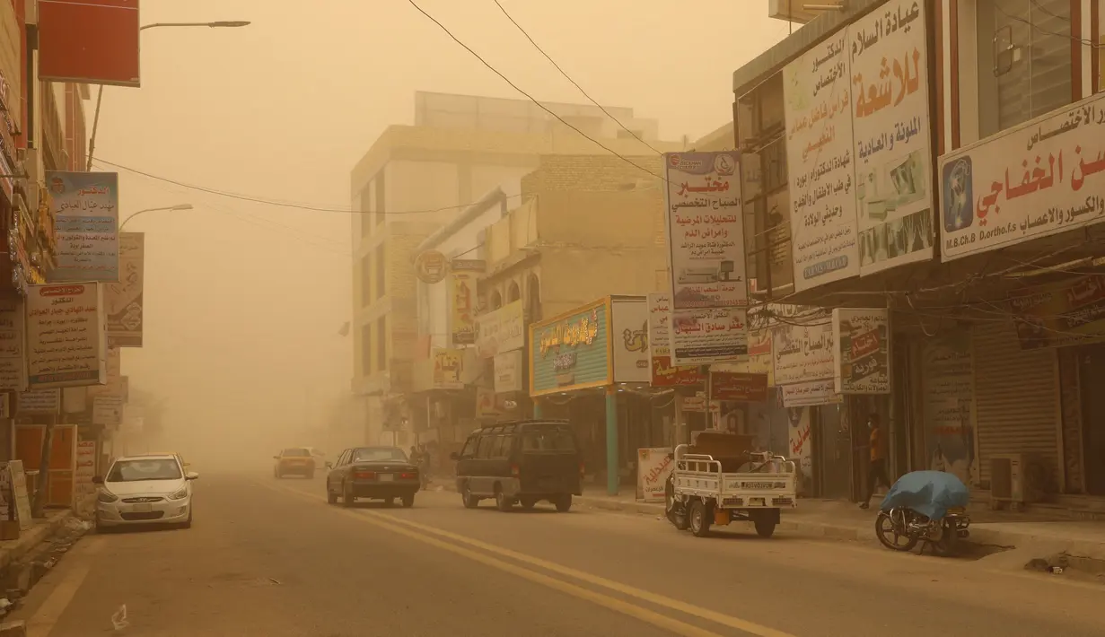 Mobil melaju di jalan selama badai debu di kota Nasiriyah Irak di provinsi Dhi Qar selatan (9/4/2022). Badai debu telah melanda sebagian besar Irak, meninggalkan puluhan orang di rumah sakit dengan masalah pernapasan. (AFP/Shwan Nawzad)