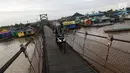 Warga melintasi jembatan penyeberangan di Sungai Martapura, Banjarmasin, Kalimantan Selatan, Selasa (27/3). Selain perahu, jembatan tersebut menjadi satu-satunya akses menyeberang bagi warga sekitar. (Liputan6.com/Immanuel Antonius)