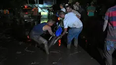 Orang-orang berusaha mengeluarkan sepeda motor yang terjebak di lumpur setelah tanah longsor akibat hujan lebat di El Castaño, Venezuela, Senin (17/10/2022). berbagai pusat pengumpulan sumbangan telah didirikan di ibu kota Venezuela untuk membantu para warga yang telah kehilangan banyak hal akibat bencana tersebut. (Federico Parra / AFP)