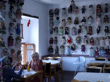 Pengunjung menikmati pesanan dengan boneka yang dipajang di kedai kopi Turki bernama Ankara Castle di Ankara, 8 Agustus 2019. Kedai kopi itu menyambut pengunjung dengan koleksi unik sebanyak 7.500 boneka porselen dari 81 negara yang dikumpulkan pemiliknya selama lebih dari 20 tahun. (Adem ALTAN/AFP)
