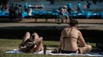 Dua wanita saat berjemur saat suhu musim panas mencapai sekitar 28 derajat di dekat Serpentine di Hyde Park di London, Inggris (5/7). (AFP Photo/Chris J Ratcliffe)