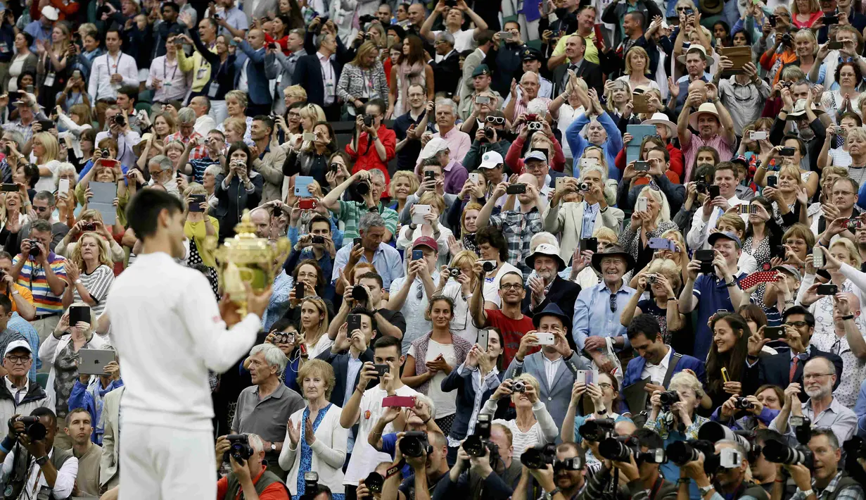 Penonton memotret Djokovic dengan trofi juara. (REUTERS/Stefan Wermuth)
