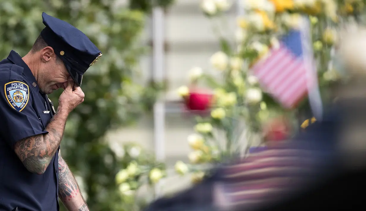 Petugas New York City Police Department (NYPD) menangis saat menghadiri upacara peringatan 16 tahun korban serangan 11 September di Museum dan Memorial Nasional 9/11, New York, Amerika Serikat, Senin (11/9). (Drew Angerer/Getty Images/AFP)