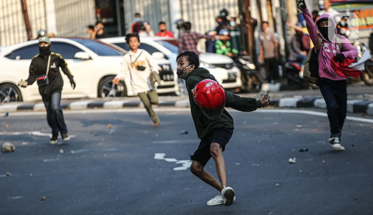 Massa melemparkan batu ke arah polisi saat bentrok di kawasan Pejompongan, Jakarta, Rabu (7/10/2020). Belum bisa dipastikan apakah aksi tersebut berkaitan dengan isu aksi penolakan pengesahan UU Omnibus Law Cipta Kerja. (Liputan6.com/Faizal Fanani)