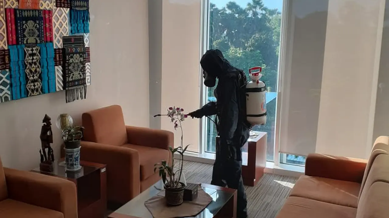 Petugas menyemprot cairan disinfektan di kantor BI NTT. (Liputan6.com/Ola Keda)