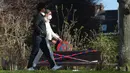 Orang-orang berjalan melewati bangku yang dipasangi garis polisi di Brussel, Belgia, pada 25 Maret 2020. Deretan bangku di sejumlah taman dilarang diduduki untuk mencegah orang-orang berkumpul atau berada terlalu lama di area publik tersebut. (Xinhua/Zheng Huansong)