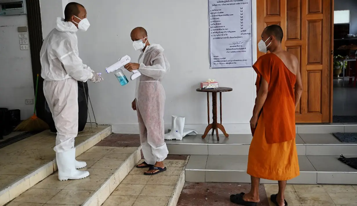 Biksu Buddha mendisinfeksi diri mereka sendiri setelah melakukan kremasi untuk korban virus corona COVID-19 di Wat Chin Wararam Worawihan, Bangkok, Thailand, 30 Juli 2021. Kasus COVID-19 di Thailand kini tengah melonjak. (Lillian SUWANRUMPHA/AFP)