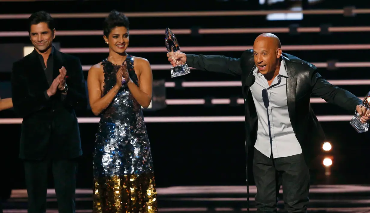 Vin Diesel menerima penghargaan untuk film favorit dan aksi film favorit bagi "Furious 7" dimana presenter John Stamos dan Priyanka Chopra bertepuk tangan untuk Vin Diesel di People's Choice Awards 2016, Los Angeles (6/1/2016). (REUTERS/Mario Anzuoni)