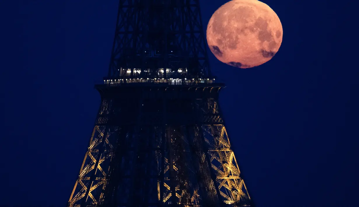 <p>Bulan purnama di bulan April, yang memiliki julukan pink moon&nbsp;atau bulan merah muda, terlihat di belakang Menara Eiffel, Paris, Selasa (23/4/2024). (Stefano RELLANDINI / AFP)</p>