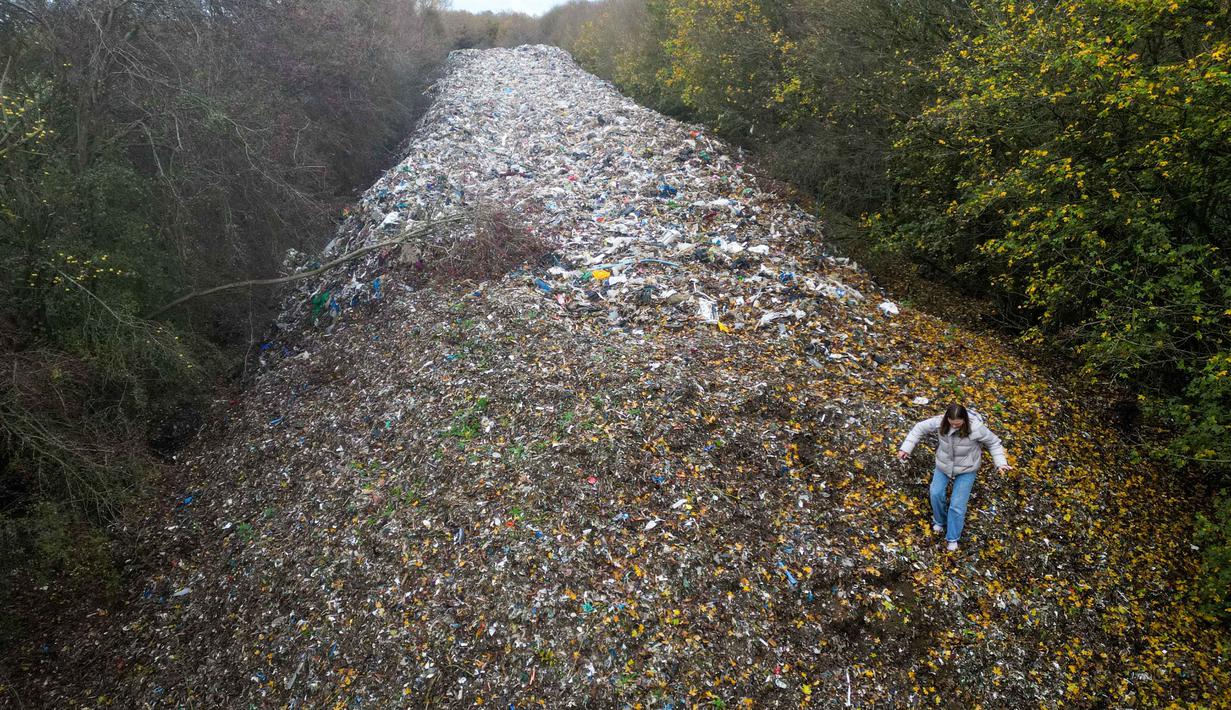 Rekaman dari pesawat tanpa awak atau drone mengungkap tumpukan sampah sepanjang lebih dari 60 meter, lebar sekitar 15 meter, dengan tinggi 10 meter. Tampak foto udara memperlihatkan aktivis lingkungan merekam konten untuk media sosial di tumpukan sampah ilegal yang besar, yang dibuang di sebuah ladang antara Sungai Cherwell dan Jalan A34 dekat Kidlington, Oxfordshire, di barat London pada 16 November 2025. (Justin TALLIS/AFP)