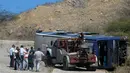 Mobil derek berusaha membalikkan sebuah bus yang terbalik di jalan raya Caracas-La Guaira, Venezuela, Rabu (10/2). Bus berisi pemain tim sepak bola Argentina Huracan itu terbalik saat menuju Bandara Internasional Simon Bolivar. (AFP/FEDERICO PARRA)