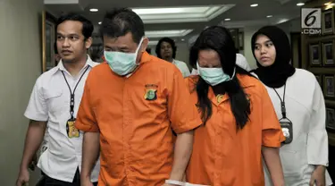 Polisi menggiring dua tersangka L dan G saat rilis tindak pidana penipuan penjualan valas di Mapolda Metro Jaya, Jakarta, Senin (10/2). Dalam kasus ini polisi mengamankan dua tersangka yang merupakan suami istri. (Merdeka.com/Iqbal Nugroho)