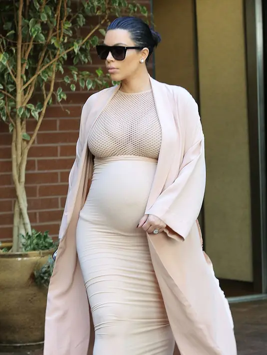 Kim tetap tampil modis dan seksi selama hamil, ia memakai mantel warna senada dengan baju ketat yang dipakainya. (via dailymail.co.uk)