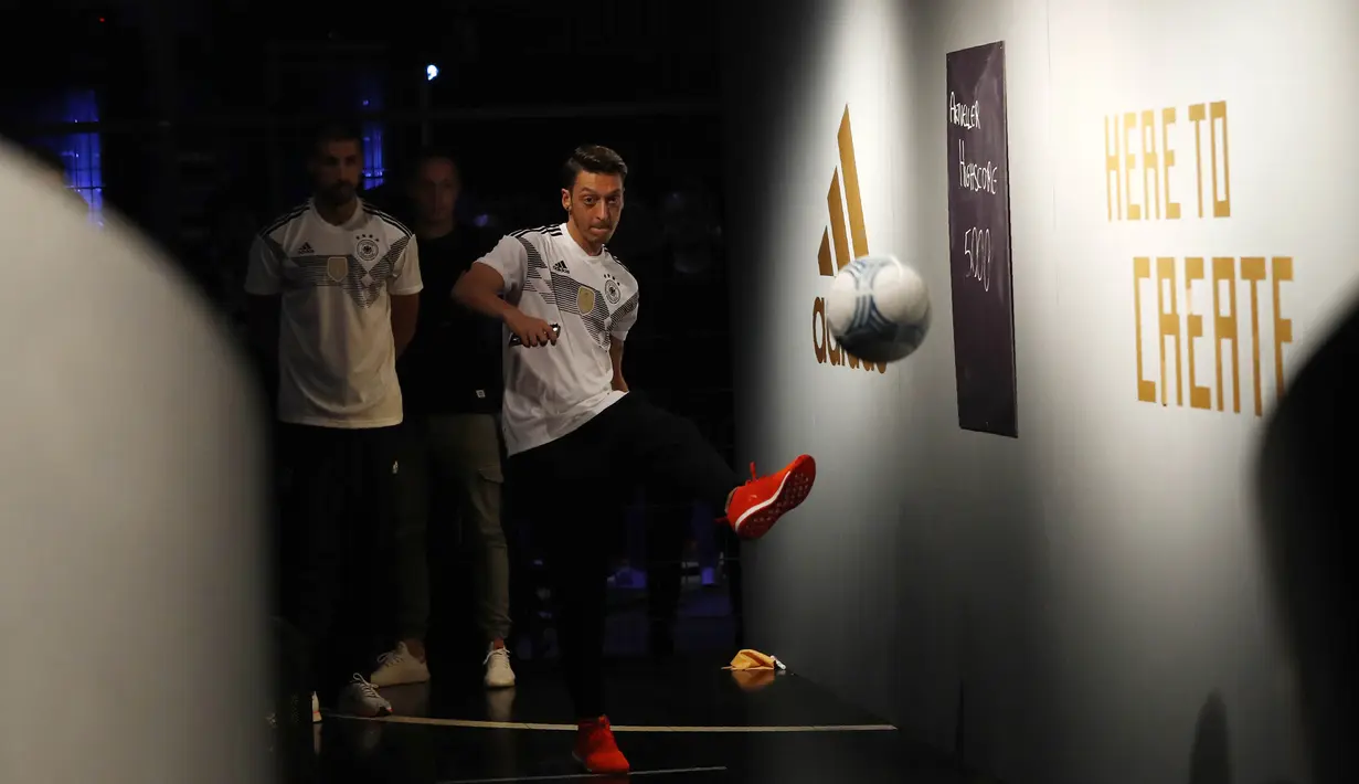 Gelandang Jerman, Mesut Ozil, menendang bola saat memperkenalkan jersey yang akan digunakan untuk Piala Dunia 2018 di Berlin, Selasa (7/11/2017). Dengan jersey ini Der Panser akan berjuang mempertahankan gelar juara dunia. (AFP/Odd Andersen)