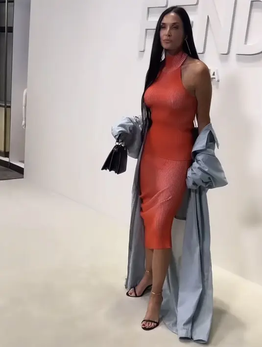 Melengkapi penampilannya yang ditata oleh stylist Brad Goreski, Moore mengenakan mantel biru-abu-abu sepanjang lantai, sepatu hak hitam dengan detail emas, dan tas tangan hitam yang serasi.  [@demimoore]