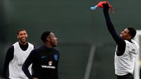Penyerang Inggris, Marcus Rashford (kanan) menangkap ayam mainan selama mengikuti sesi latihan di Repino, Rusia (10/7). Inggris akan bertanding melawan Kroasia pada babak semifinal Piala Dunia 2018. (AFP Photo/Adrian Dennis)