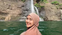 Alam bebas selalu dieksplor oleh Alifhia Fitri termasuk keindahan air terjun. Pesona senyum manis Fhia saat berenang di air terjun ini sukses bikin banyak orang terpesona. Tidak heran meski berenang di air terjun, kecantikan Alifhia Fitri tetap terlihat dan berhasil curi perhatian. (Liputan6.com/IG/@alifhiafitri)
