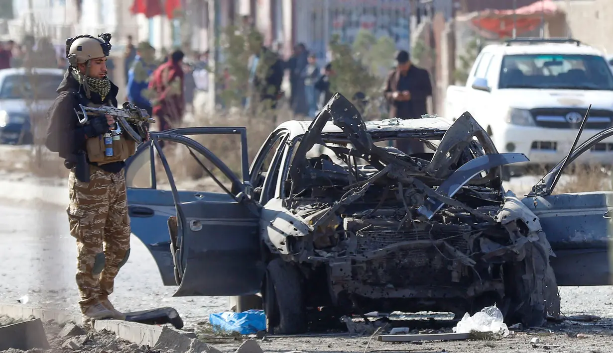 Seorang tentara berdiri di samping kendaraan yang rusak setelah serangan bom mobil di Kabul, Afghanistan (13/11/2019). Setidaknya tujuh orang tewas dan tujuh lainnya luka-luka ketika sebuah bom mobil meledak pada jam sibuk pagi hari Kabul pada 13 November. (AFP/STR)