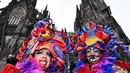 Perempuan dengan kostum warna-warni berpose di depan katedral Cologne saat puluhan ribu orang menyambut dimulainya musim karnaval di jalan-jalan Kota Cologne, Jerman, Senin (11/11/2019). Musim karnaval ini dikenal juga sebagai musim kelima dalam satu tahun. (AP Photo/Martin Meissner)