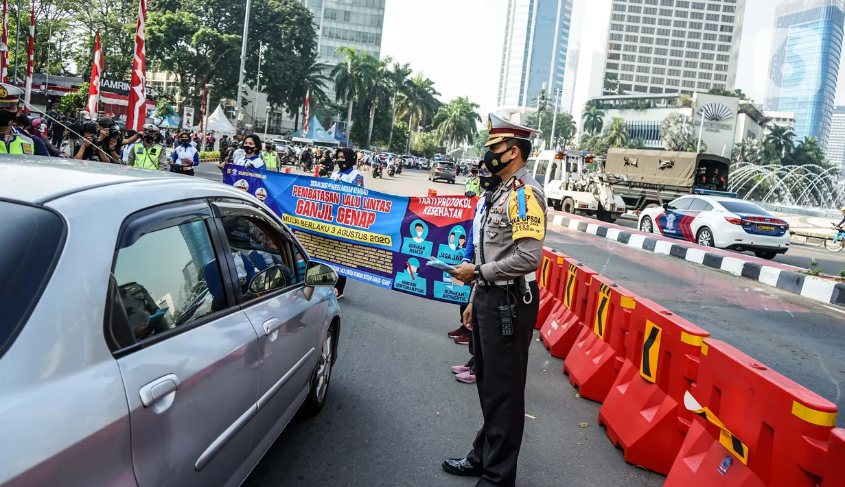 Petugas kepolisian membentangkan spanduk saat sosialisasi pelaksanaan ganjil genap di Kawasan Bundaran HI, Jakarta, Minggu (2/8/2020). Ditlantas Polda Metro Jaya kembali memberlakukan sistem ganjil genap di 25 ruas jalan protokol  DKI Jakarta mulai Senin, 3 Agustus 2020. (Liputan6.com/Faizal Fanani)