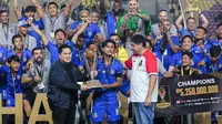 Kapten tim Arema FC, Ahmad Alfarizi, menerima trofi juara Piala Presiden 2024 dari Ketua Umum PSSI, Erick Thohir, disaksikan oleh Ketua Steering Committee (SC) Piala Presiden, Maruarar Sirait, di depan pemain-pemain Singo Edan yang siap berselebrasi di Stadion Manahan Solo, Minggu (4/8/2024). (Bola.com/Bagaskara Lazuardi)