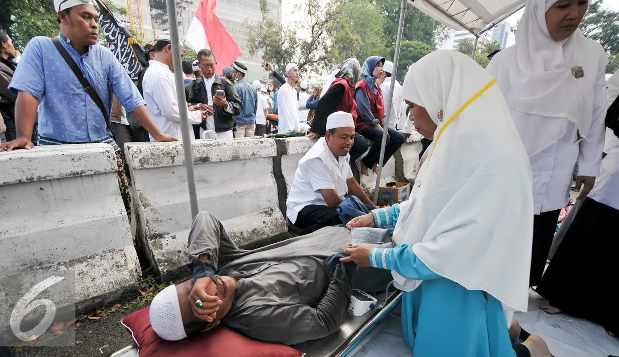 Seorang demonstran yang kelelahan diberikan pertolongan, Jakarta, Jumat (4/11). Massa yang datang ke posko ini rata-rata yang usianya sudah separuh baya, di atas 45 tahun. (Liputan6.com/Yoppy Renato)