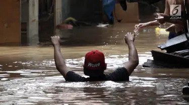 Warga melintasi banjir di Jalan Kebon Pala, Kampung Melayu, Jatinegara, Jakarta Timur, Rabu (7/2). Setelah sempat surut, banjir kembali merendam permukiman warga dengan ketinggian air mencapai sekitar 170 cm. (Liputan6.com/Arya Manggala)