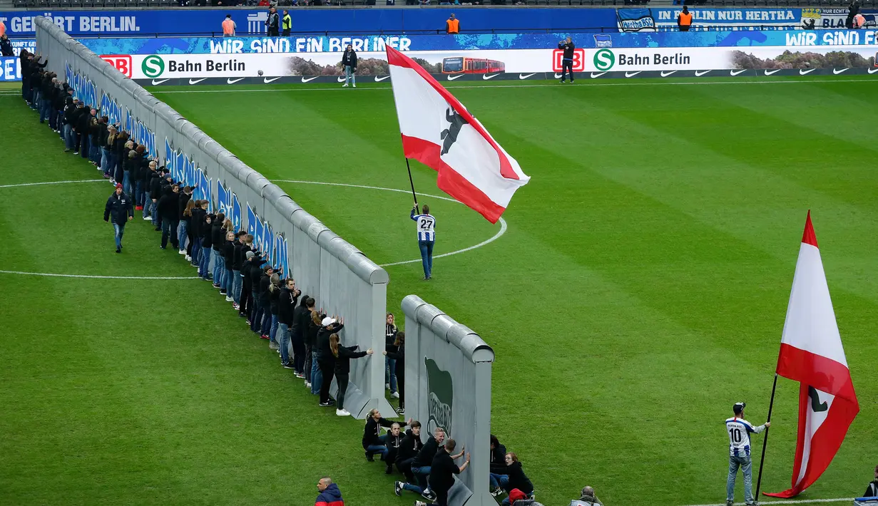 Para penggemar mengambil bagian dalam pertunjukan replika Tembok Berlin pada hari peringatan 30 tahun runtuhnya Tembok Berlin sebelum pertandingan Hertha Berlin melawan RB Leipzig di Stadion Olimpiade, Berlin (9/11/2019). (AFP/Odd Andersen)