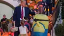 Presiden AS, Donald Trump dan ibu negara Melania Trump membagikan permen kepada anak-anak selama acara trick-or-treat Halloween di South Lawn, Gedung Putih, Senin (28/10/2019). Trump dan Melania terlihat memberikan tas-tas hadiah untuk anak-anak yang menggunakan beragam kostum. (AP/Alex Brandon)