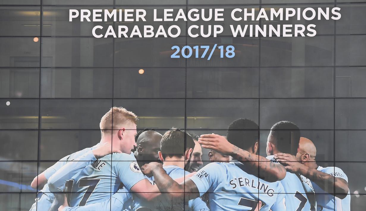 Poster raksasa bergambar pemain Manchester City terpasang di Stadion Etihad, Manchester, Senin (17/4/2018). Persiapan ini dilakukan untuk merayakan pesta juara Manchester City meraih gelar Premier League. (AFP/Paul Ellis)