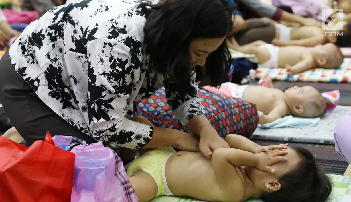 Seorang ibu memijat anaknya dalam acara pijat massal bayi di Gedung Kementerian Kesehatan, Jakarta, Selasa (7/11). Acara dalam rangka menyambut Hari Kesehatan Nasional ini diikuti 300 bayi dan anak bawah dua tahun. (Liputan6.com/Immanuel Antonius)