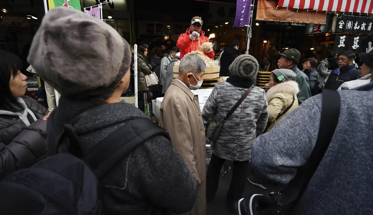 Wisatawan dan warga yang sedang mencari bahan-bahan untuk membuat makanan tahun baru atau osechi memenuhi jalanan Pasar Tsukiji, Tokyo, Jepang, Kamis (26/12/2019). Di zaman sekarang, osechi sering berarti makanan mewah untuk tahun baru. (AP Photo/Eugene Hoshiko)