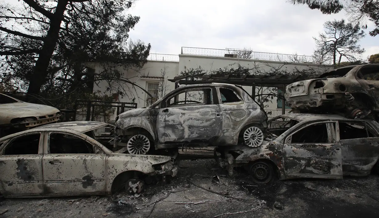 Mobil-mobil yang terbakar berserakan di sepanjang sisi jalan di Desa Mati, timur Athena, Selasa (24/7). Kebakaran hutan diperparan dengan embusan angin kencang. (AP Photo/Thanassis Stavrakis)