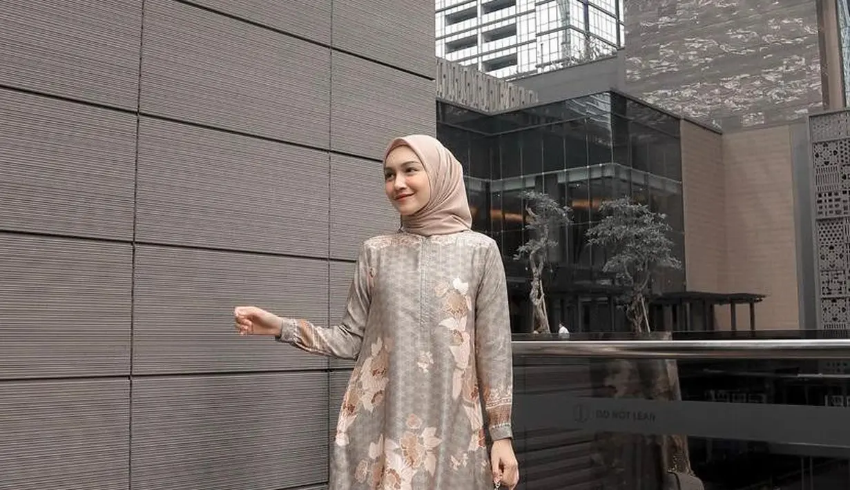 Gaya Melody Prima dengan silk dress bermotif nuansa warna sage green dan coklat yang dipadukan dengan hijab warna coklat beri tampilan elegan. (Instagram/melodyprima).