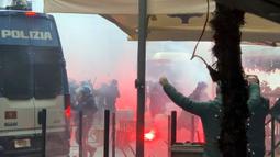 Suporter Eintracht Frankfurt melempari polisi antihuru-hara dengan kursi hingga suar. (Stefano Gattordo/LaPresse via AP)