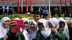 Sejumlah pelajar ber-selfi seusai mengikuti upacara memperingati Hari Pendidikan Nasional di Jakarta, Sabtu (2/5/2015). Peringatan tersebut mengangkat tema 'Gerakan Pencerdasan dan Penumbuhan Generasi Berkarakter Pancasila'. (Liputan6.com/Johan Tallo)