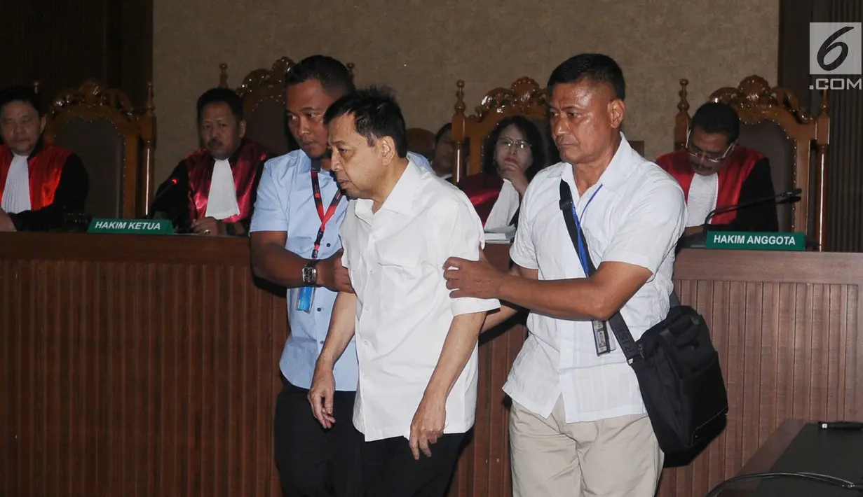 Tersangka korupsi e-KTP, Setya Novanto dipapah petugas saat memasuki ruang sidang Pengadilan Tipikor, Jakarta, Rabu (13/12). Sidang tersebut dipimpin oleh Ketua Majelis Hakim Yanto. (Liputan6.com/Helmi Fithriansyah)