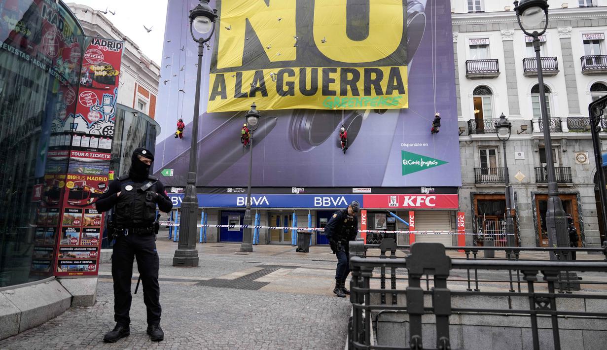 Hingga, Selasa 10 Maret 2026, konflik ini telah memasuki hari kesepuluh dengan eskalasi yang terus meningkat di berbagai wilayah. Tampak dalam foto, petugas polisi membentuk perimeter saat aktivis Greenpeace membentangkan spanduk besar bertuliskan "Tidak untuk Perang" sebagai bentuk protes terhadap serangan Amerika Serikat (AS) dan Israel terhadap Iran, di Lapangan Puerta del Sol, Madrid, Spanyol, pada Selasa 10 Maret 2026. (Paul Hanna/AFP)