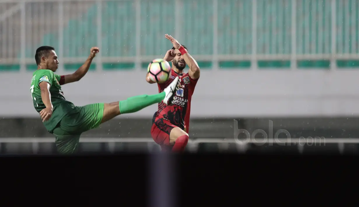 Pemain PS TNI , Andy Nugroho (kiri) membuang bola dari kejaran pemain Persiba Balikapapan, Anmar Almubaraki pada Liga 1 2017 di Stadion Pakansari, Bogor, Jumat (5/5/2017). PS TNI dan Persiba bermain imbang 1-1.  (Bola.com/Nicklas Hanoatubun)