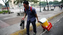 Seorang penjual kopi berjalan saat terjadi bentrokan antara pasukan keamanan dan penentang Presiden Nicolas Maduro di Caracas, Venezuela, (26/3). (AP Photo / Ariana Cubillos)