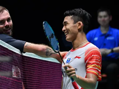 Tunggal putra Indonesia, Jonatan Christie tersenyum saat bersalaman dengan Jan O Jorgensen  dari Denmark usai bertanding dalam babak semifinal Jepang Terbuka 2019  di Tokyo (27/7/2019). Jonatan Christie akan melawan Kento Momota dari Jepang di babak final. (AFP Photo/Toshifumi Kitamura)