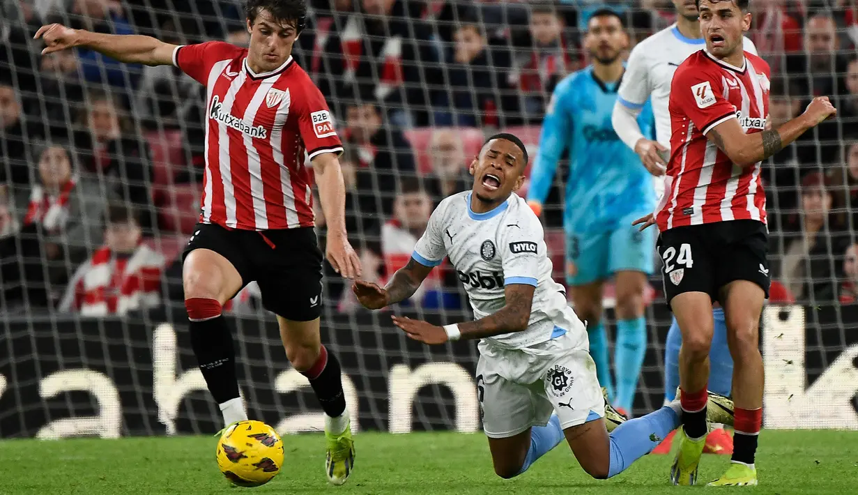 Ekspresi kesakitan pemain Girona, Savio Moreira saat berusaha melewati pemain Athletic Bilbao pada laga lanjutan Liga Spanyol 2023/2024 di San Mames Stadium, Bilbao, Spanyol, Selasa (20/02/2024) dini hari WIB. (AFP/Ander Gillenea)