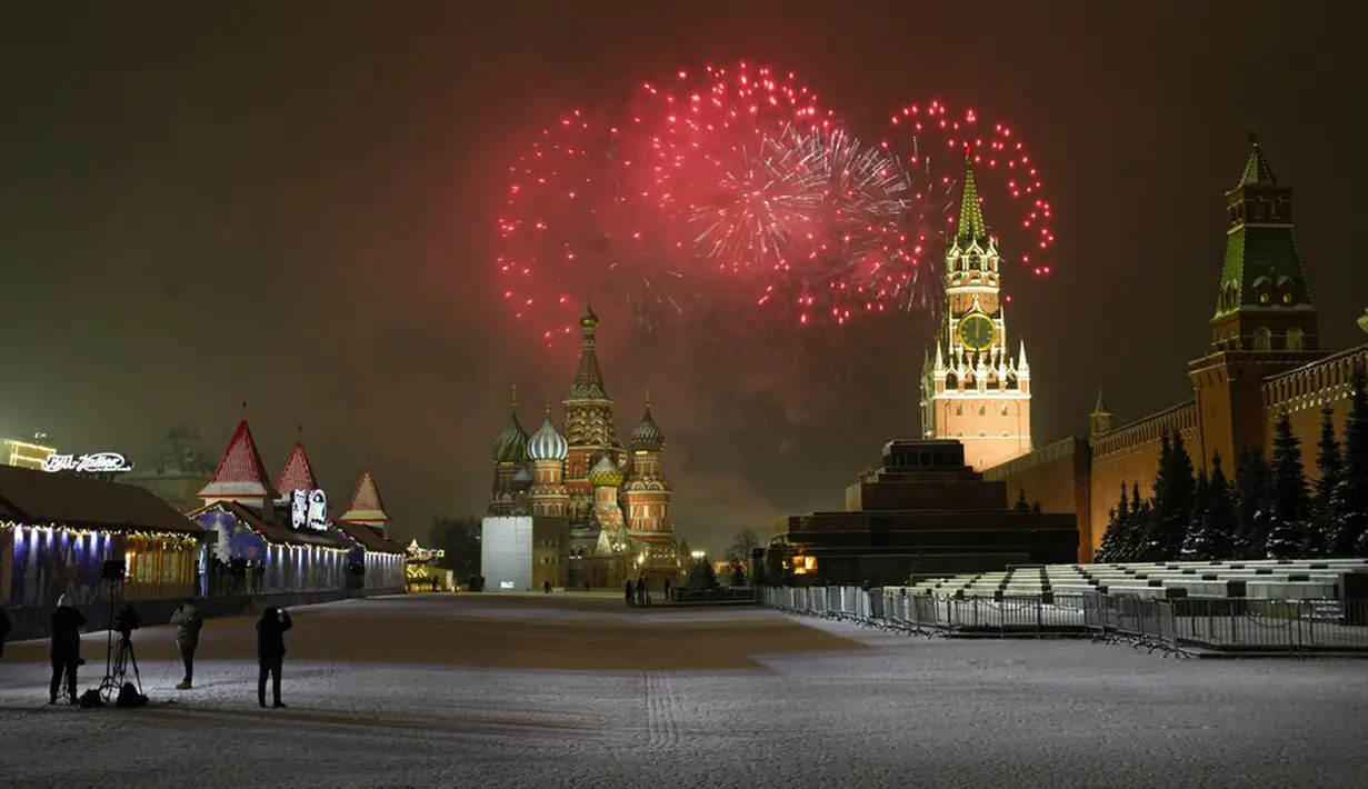 Wartawan menyaksikan kembang api meledak di atas Katedral St. Basil dan Kremlin dengan Menara Spasskaya di Lapangan Merah yang kosong karena pembatasan pandemi COVID-19 saat perayaan Tahun Baru di Moskow, Rusia, Sabtu (1/1/2022). (AP Photo/Alexander Zemlianichenko Jr)