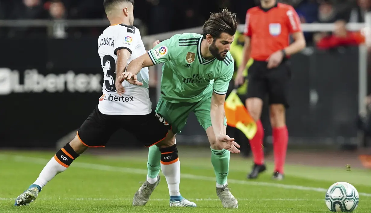 Bek Real Madrid, Nacho (kanan) berusaha melewati pemain Valencia, Jaume Costa pada pertandingan lanjutan La Liga Spanyol di Stadion Mestalla (15/12/2019). Madrid bermain imbang 1-1 atas Valencia. (AP Photo/Alberto Saiz)
