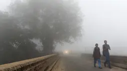 Pelajar India berjalan menuju sekolah saat kabut asap akibat polusi udara menyelimuti New Delhi, Rabu (8/11). Indian Medical Association menyarankan warga untuk tidak keluar rumah dan menghindari sedapat mungkin aktivitas fisik apapun. (PRAKASH SINGH/AFP)