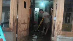 Seorang warga membersihkan rumah dari sisa-sisa genangan air yang merendam pemukiman mereka di kawasan Kampung Pulo, Jatinegara, Jakarta Timur, Selasa (10/2/2015). (Liputan6.com/Herman Zakharia)