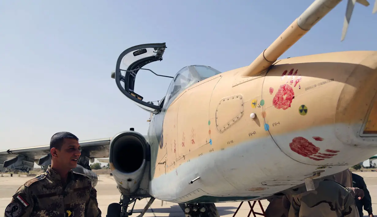 Salah satu anggota militer Irak terlihat mengamati pesawat jet jenis Sukhoi Su-25 yang baru tiba di Pangkalan Udara al-Muthanna, Baghdad, (1/7/2014). (REUTERS/ Stringer) 
